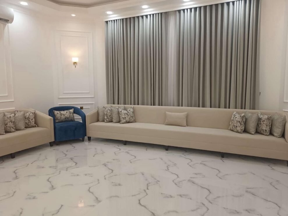 Beige sofa set with a navy accent chair on marble flooring